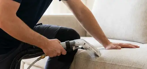Professional upholstery cleaner deep-cleaning a fabric sofa with a handheld extraction tool, Fort Collins, CO.